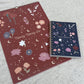Two planners with floral and celestial designs on a textured surface