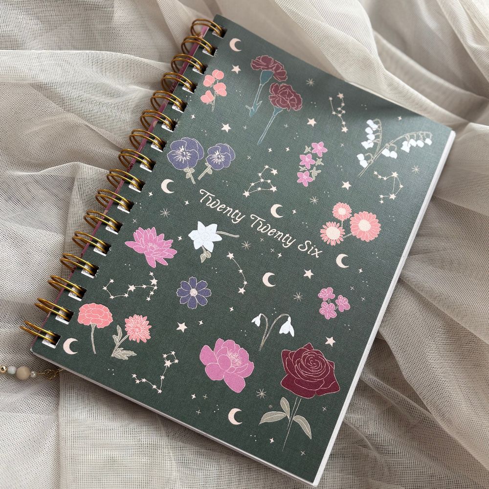Forest green planner with floral and celestial design on a sheer fabric background